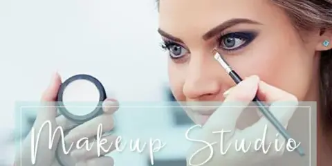 A makeup artist applying eye makeup to a client using a brush and a compact mirror.