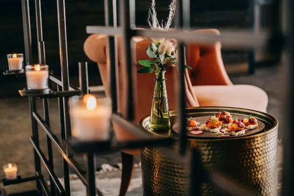 A plated appetizer garnished with fresh herbs and a small floral arrangement in a glass vase, set on a metallic table.
