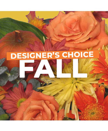 A close-up of a fall floral arrangement featuring orange roses, yellow chrysanthemums, and a small pumpkin.