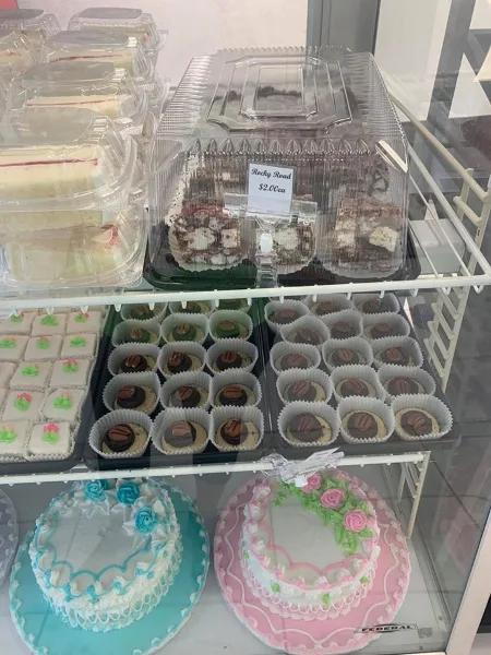 A display case filled with various cakes, cupcakes, and pastries, including a blue and a pink decorated cake.