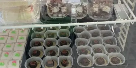 A display case filled with various cakes, cupcakes, and pastries, including a blue and a pink decorated cake.