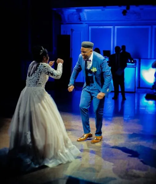 A bride and groom dancing on a dance floor with a DJ in the background.