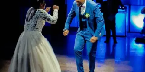 A bride and groom dancing on a dance floor with a DJ in the background.