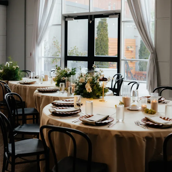 Round reception tables with bronze linens beside tall arched windows at Vue Columbus