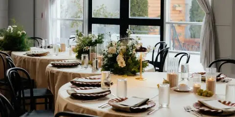 Round reception tables with bronze linens beside tall arched windows at Vue Columbus
