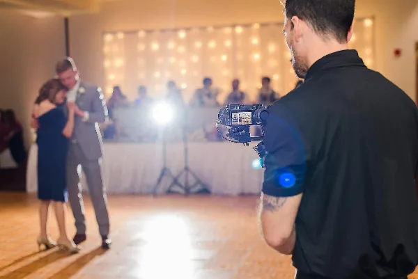 A videographer films a couple dancing at a wedding reception.
