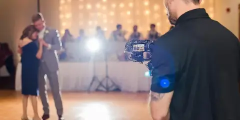 A videographer films a couple dancing at a wedding reception.