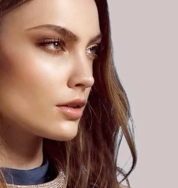Close-up portrait of a woman with professional makeup and styled hair.