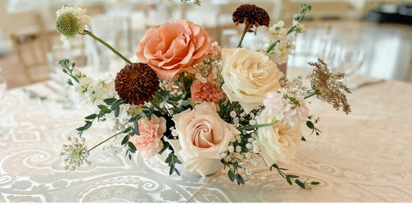Elegant floral centerpiece with roses and delicate blooms on a decorated table.