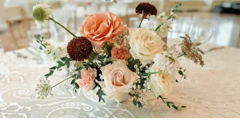 Elegant floral centerpiece with roses and delicate blooms on a decorated table.