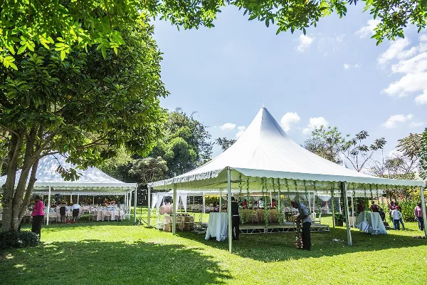 A large white event tent set up on a grassy lawn with tables and chairs visible underneath.