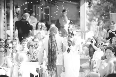 A wedding officiant performing a ceremony for a couple in front of seated guests.