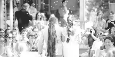 A wedding officiant performing a ceremony for a couple in front of seated guests.