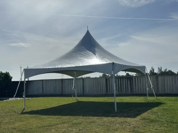 A large white event tent set up on a grassy lawn under a blue sky.