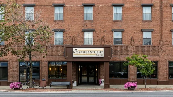 Exterior view of The Northeastland Hotel, a multi-story red brick building with a central entrance and signage.