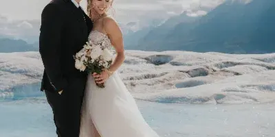 Bride and groom standing together on an Alaskan glacier, with the bride holding a bouquet.