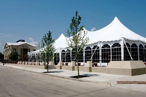 Exterior view of a large white event tent and a building labeled Town Hall under a clear blue sky.