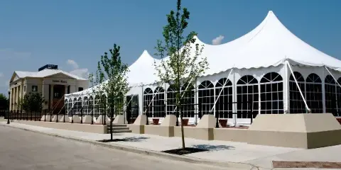 Exterior view of a large white event tent and a building labeled Town Hall under a clear blue sky.