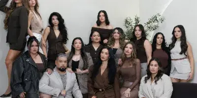 Group of professionally styled women and one man posing in a studio with neutral tones and modern decor.