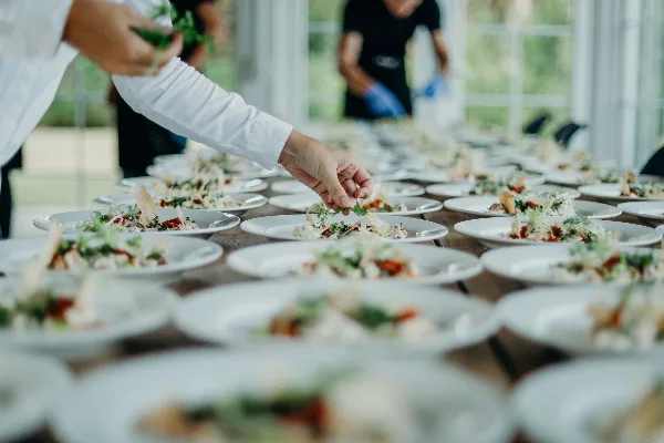 Catering staff plating multiple dishes for an event
