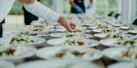 Catering staff plating multiple dishes for an event