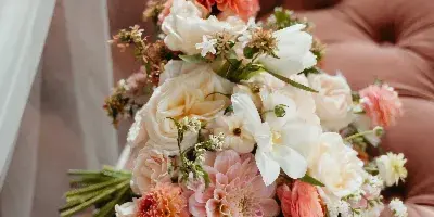 A close-up of a wedding bouquet with pink and white flowers resting on a tufted velvet surface.