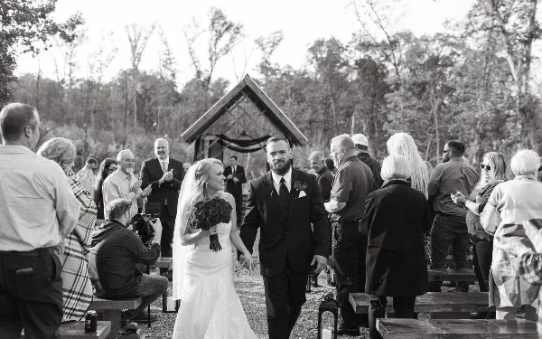 A bride and groom walking down the aisle at an outdoor wedding ceremony.