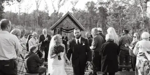 A bride and groom walking down the aisle at an outdoor wedding ceremony.