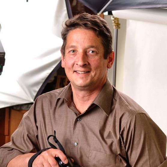Portrait of a male photographer holding a camera in a studio.