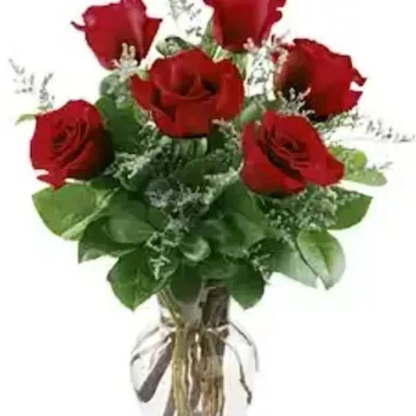 A bouquet of red roses with greenery in a clear glass vase