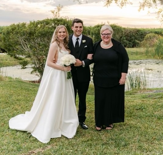 A bride and groom standing with their officiant outdoors after a wedding ceremony.