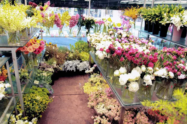 Interior view of a florist shop with shelves and tables filled with colorful fresh flowers and bouquets.
