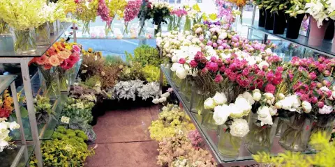 Interior view of a florist shop with shelves and tables filled with colorful fresh flowers and bouquets.