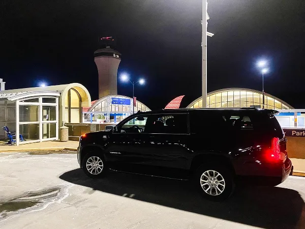 A black luxury SUV parked at an airport terminal at night.