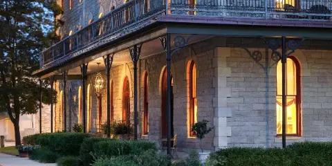 Exterior view of the Historic Elgin Hotel in Marion, Kansas, showcasing the restored 19th-century limestone architecture, wraparound porch, and glowing windows at dusk.