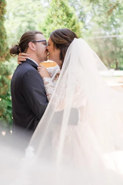 A bride and groom sharing a kiss during a wedding portrait session outdoors.