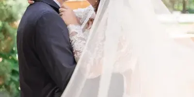 A bride and groom sharing a kiss during a wedding portrait session outdoors.