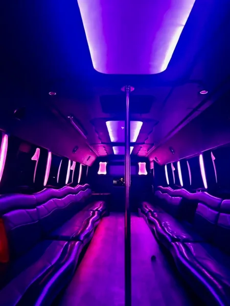 Interior of a luxury party bus with leather bench seating and purple ambient LED lighting