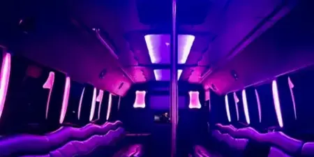 Interior of a luxury party bus with leather bench seating and purple ambient LED lighting