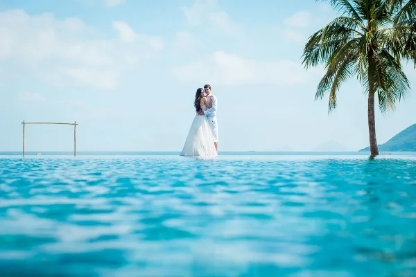 A bride and groom standing in an infinity pool at a tropical destination wedding location.