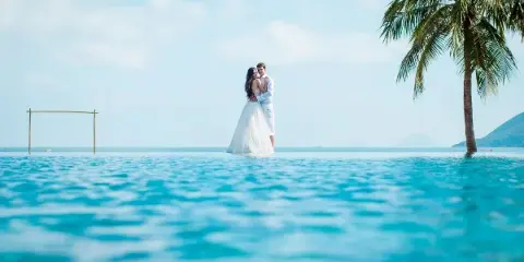 A bride and groom standing in an infinity pool at a tropical destination wedding location.