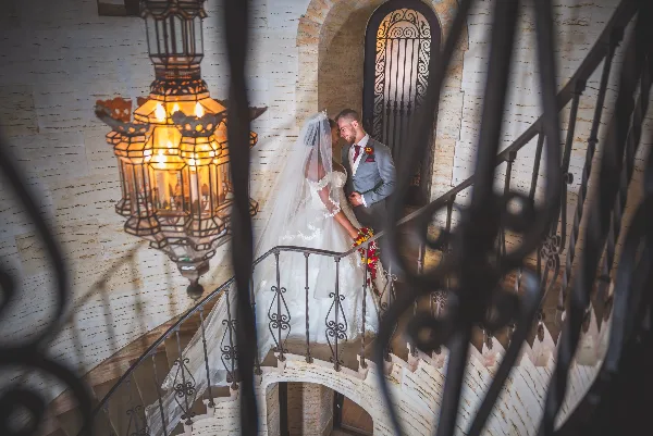 A bride and groom standing on a stone staircase with a decorative lantern in the foreground.