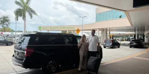 A black SUV parked at the curb of Sarasota Bradenton International Airport with a passenger and luggage.