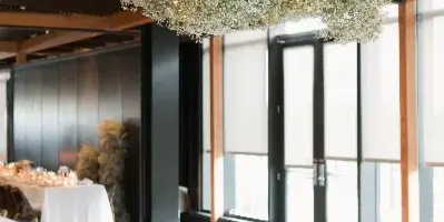 A large, cloud-like floral arrangement of white gypsophila suspended from the ceiling of a modern event venue.