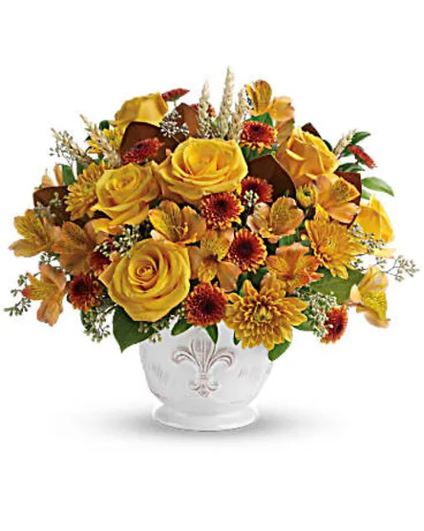 A vibrant floral arrangement featuring yellow roses, alstroemeria, and dahlias in a white ceramic vase.