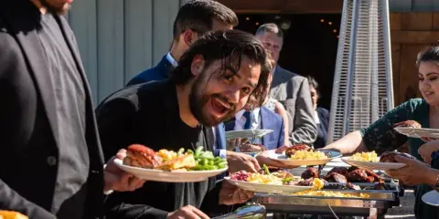 Catering staff serving food to guests at an outdoor event