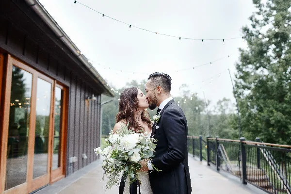 Wedding couple holding a white floral bouquet by Petals and Twigs