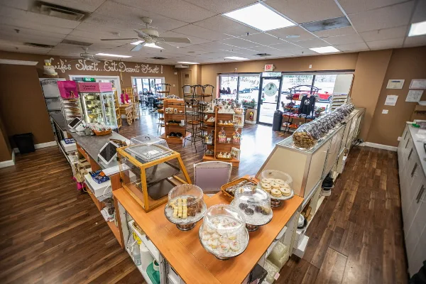 Interior view of a bakery with wooden display cases filled with assorted pastries, cakes, and cookies.