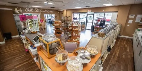 Interior view of a bakery with wooden display cases filled with assorted pastries, cakes, and cookies.