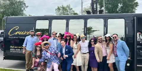 A group of people posing in front of a black Cruze Transport party bus